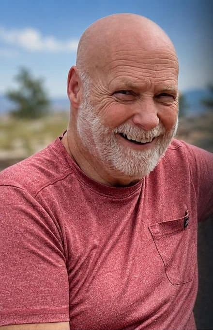 Jim Carpenter outdoors, smiling, in a red shirt.