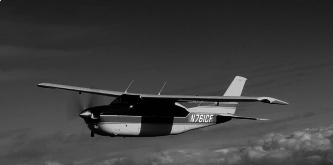 A Cessna Turbo 210 Centurion in flight, the registration N761CF on its fuselage, photographed in black and white.